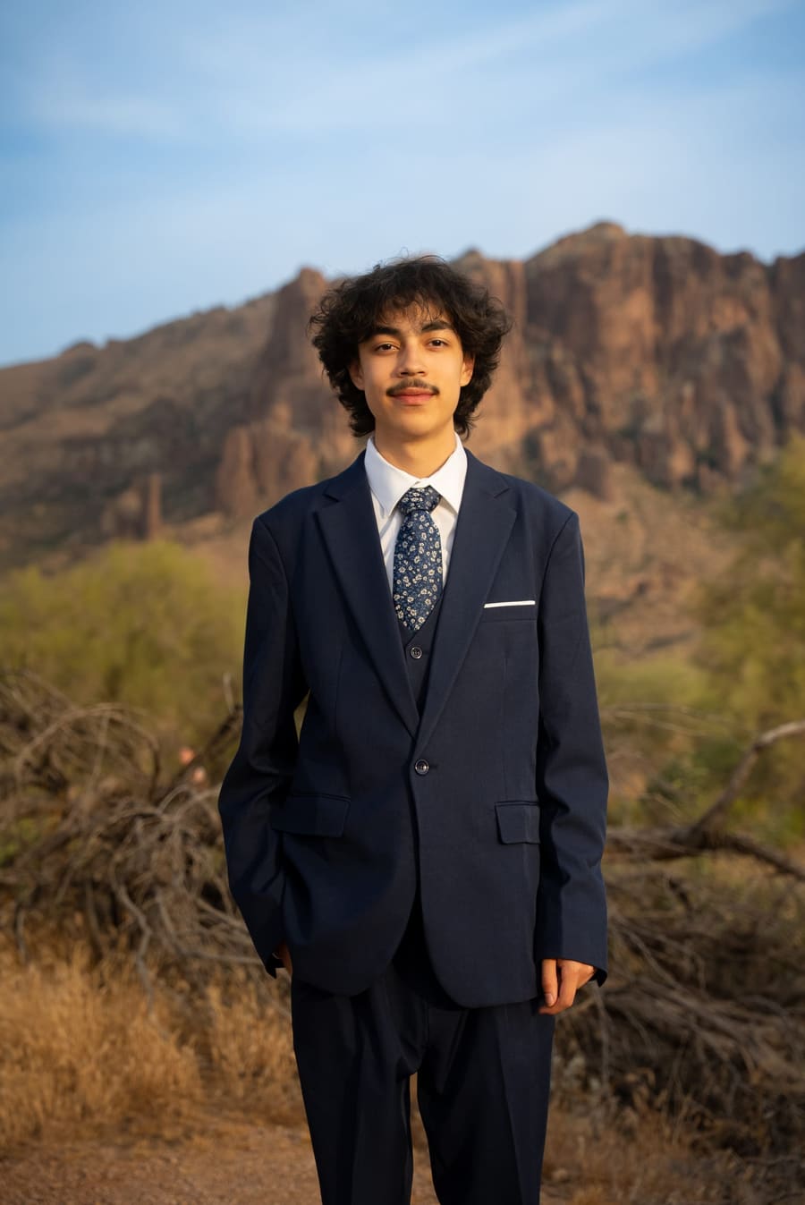 Portrait of a young man in a suit with desert mountains behind him