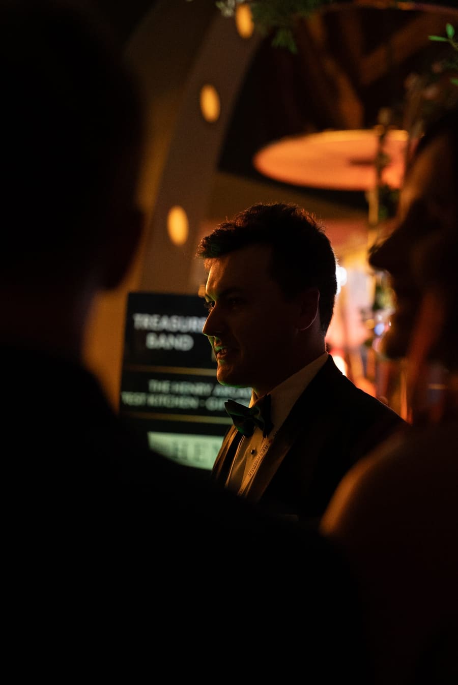 Guest in a tuxedo in silhouette at a dimly lit gala