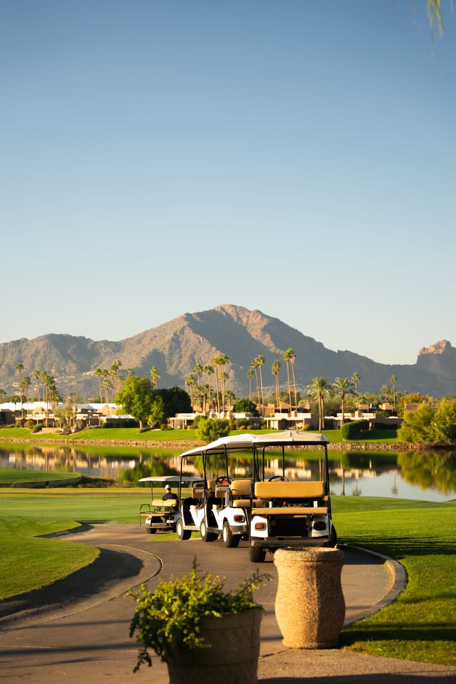 Golf carts beside a pond with Camelback Mountain in the distance