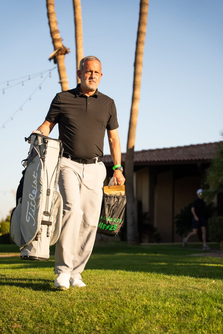 Golfer carrying his bag across the grass at sunset