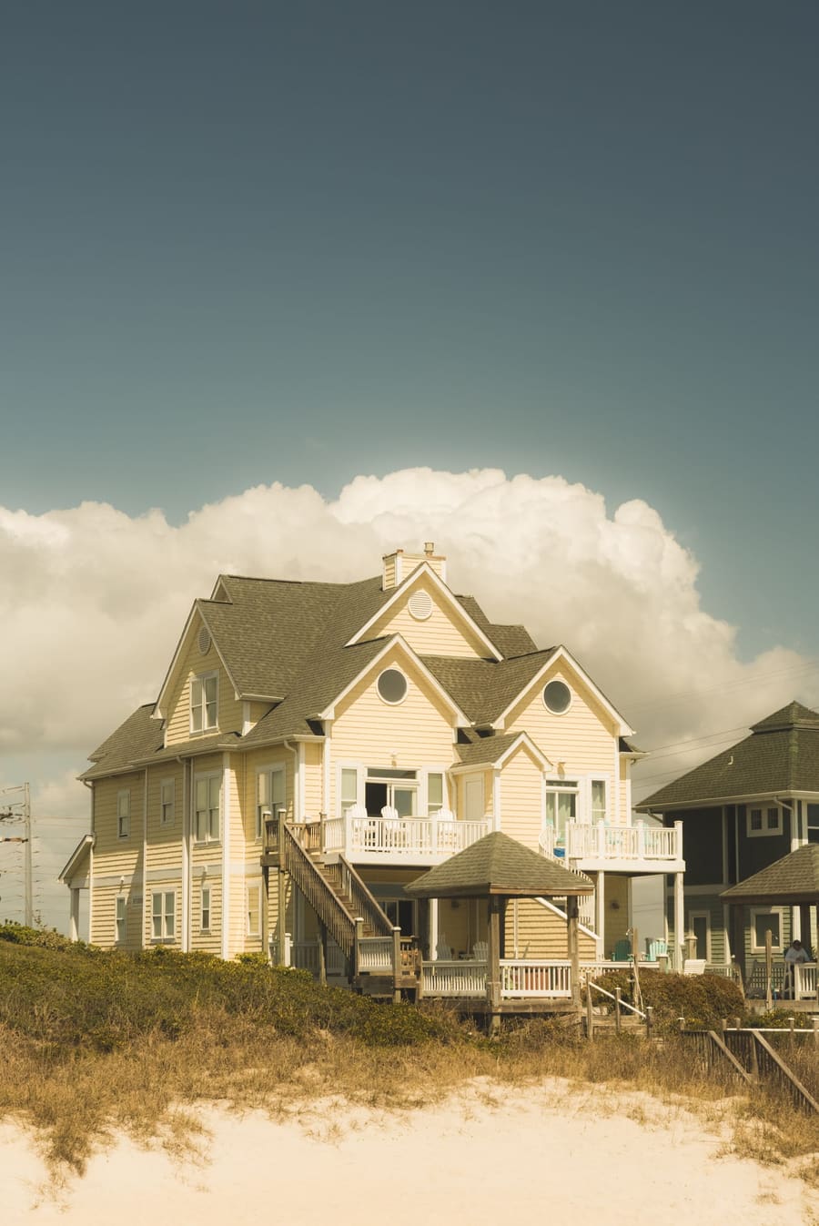 Beach house on the dunes beneath billowing clouds