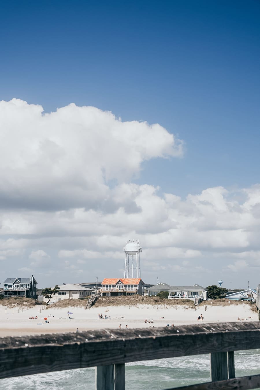 Beach and water tower under a deep blue sky with big clouds