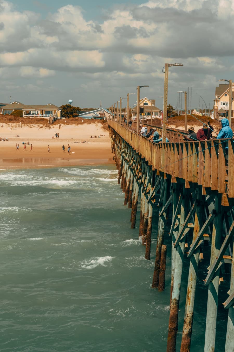 Fishing pier stretching over green surf beside the beach